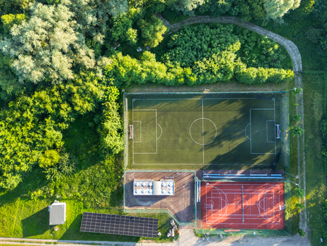 Aerial view of a soccer field and a basketball court surrounded by lush green trees and vegetation in Suchacz Warmian Masurian Voiv Poland. Aerial view of a soccer field and a basketball court surrounded by lush green trees and vegetation in Suchacz Warmian Masurian Voiv Poland.