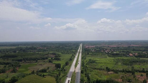 Aerial view of the toll road stretching through the lush green rural landscape and agricultural fields of Cipeundeuy West Java Indonesia. Aerial view of the toll road stretching through the lush green rural landscape and agricultural fields of Cipeundeuy West Java Indonesia.