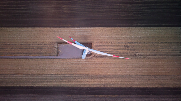 Aerial view of a wind turbine standing in a vast agricultural field with striped patterns of soil in Vladimirovac Vojvodina Serbia. Aerial view of a wind turbine standing in a vast agricultural field with striped patterns of soil in Vladimirovac Vojvodina Serbia.