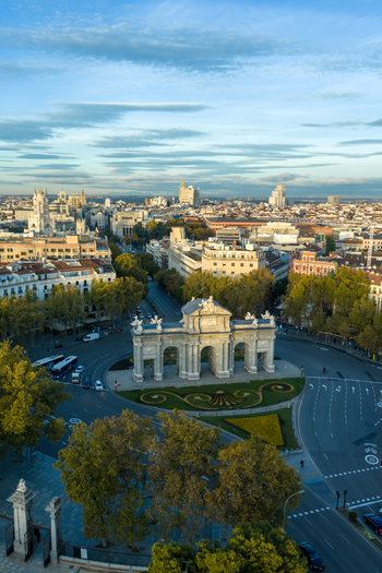 Aerial view of the historic Puerta de Alcala monument surrounded by city streets lush trees and urban architecture in Madrid Community of Madrid Spain.