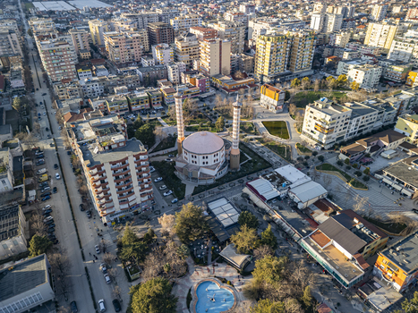 Aerial view of Fier Mosque surrounded by urban buildings streets and a small park in the city center of Fier Fier County Albania. Aerial view of Fier Mosque surrounded by urban buildings streets and a small park in the city center of Fier Fier County Albania.