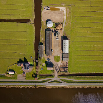 Aerial view of a farmstead nestled amidst a vibrant patchwork of green fields and dark waterways Wormer Netherlands. Aerial view of a farmstead nestled amidst a vibrant patchwork of green fields and dark waterways Wormer Netherlands.