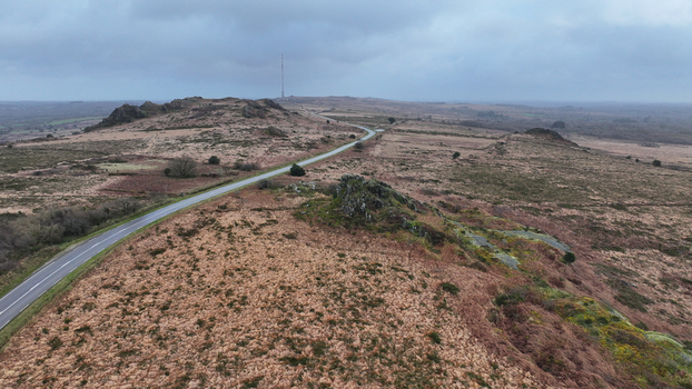 Aerial view of Roc h Trevezel peak and the winding road through the moorland landscape of Monts d Arree under a cloudy sky Plouneour Menez Brittany France.