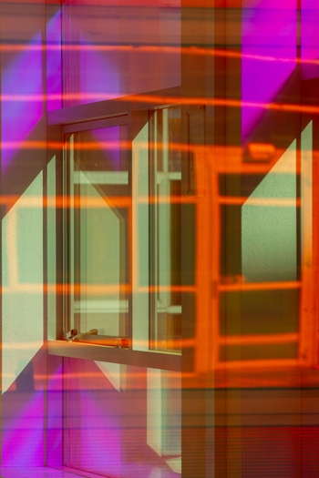 View of open window bathed in a vibrant geometric dance of purple and orange light casting bold shadows across the wall La Defense Flevoland Netherlands. View of open window bathed in a vibrant geometric dance of purple and orange light casting bold shadows across the wall La Defense Flevoland Netherlands.
