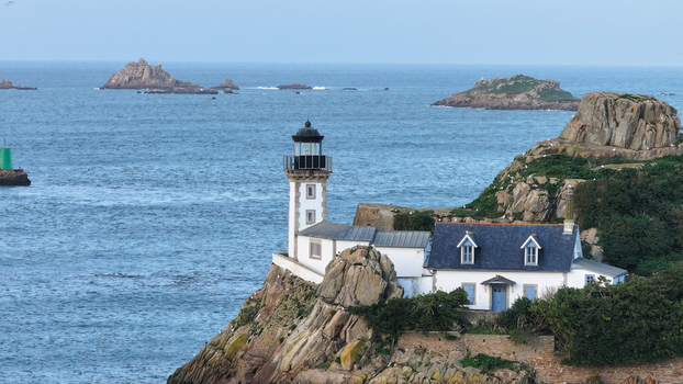Aerial view of Louet island featuring the lighthouse and keeper s cottage on rocky cliffs overlooking the sea Carantec Brittany France. Aerial view of Louet island featuring the lighthouse and keeper s cottage on rocky cliffs overlooking the sea Carantec Brittany France.