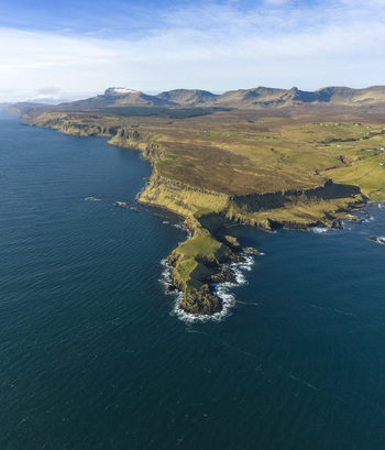 Aerial view of The Brother s Point featuring rugged cliffs and a grassy peninsula jutting into the deep blue sea under a clear sky Culnacnoc Scotland United Kingdom. Aerial view of The Brother s Point featuring rugged cliffs and a grassy peninsula jutting into the deep blue sea under a clear sky Culnacnoc Scotland United Kingdom.
