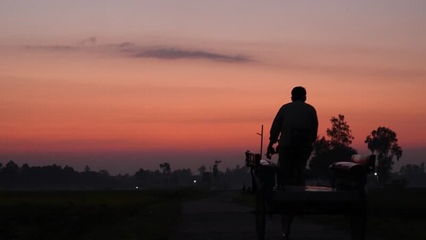 View of a rickshaw puller silhouette at sunset in Bogura Bangladesh. View of a rickshaw puller silhouette at sunset in Bogura Bangladesh.