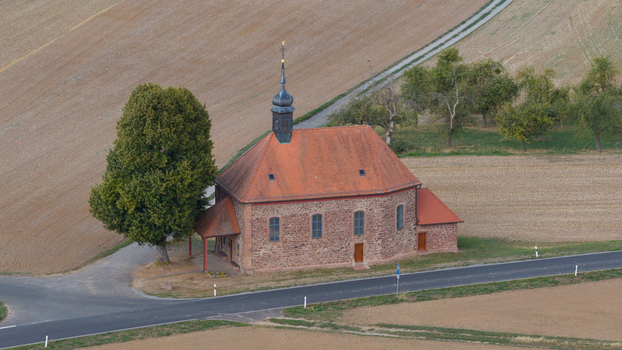 Aerial view of Wendelinuskapelle a historic stone chapel with a red tiled roof situated near a road surrounded by agricultural fields in Dieburg Hessen Germany. Aerial view of Wendelinuskapelle a historic stone chapel with a red tiled roof situated near a road surrounded by agricultural fields in Dieburg Hessen Germany.