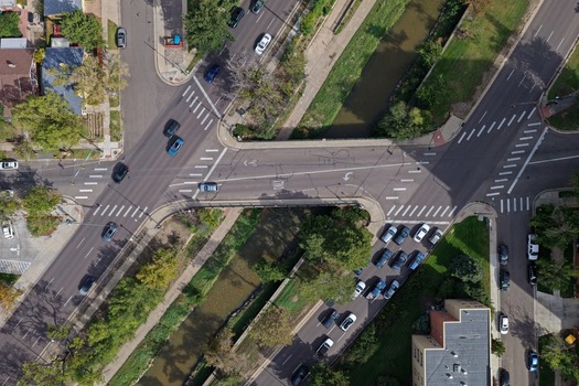 Aerial view of Cherry Creek flowing under a road intersection with traffic and surrounding urban greenery in Denver Colorado United States. Aerial view of Cherry Creek flowing under a road intersection with traffic and surrounding urban greenery in Denver Colorado United States.