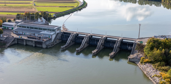 Aerial view of a hydroelectric power plant and dam on a river with solar panels and concrete spillway gates Slovenia.