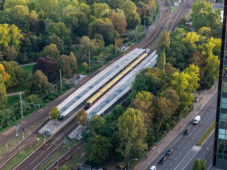 Aerial view of Berlin Treptower Park featuring the S Bahn train station with tracks lush green trees and a nearby road with traffic in Berlin Berlin Germany. Aerial view of Berlin Treptower Park featuring the S Bahn train station with tracks lush green trees and a nearby road with traffic in Berlin Berlin Germany.