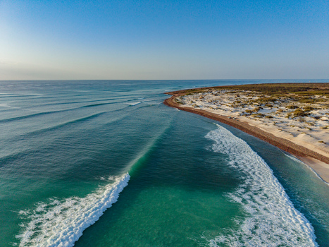 Aerial view of the azure waters meeting the sandy shore in a dance of light and foam contrasting with the arid landscape Kadrihnitin Socotra Yemen. Aerial view of the azure waters meeting the sandy shore in a dance of light and foam contrasting with the arid landscape Kadrihnitin Socotra Yemen.
