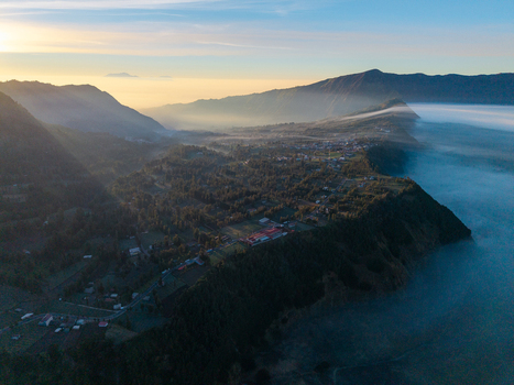Aerial view of Cemorolawang village in the mountainous landscape of East Java surrounded by morning mist and golden hour light Kecamatan Sukapura Jawa Timur Indonesia.