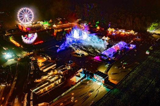 Herzogenaurach Germany 22 July 2022 Aerial view of Open Beatz Festival with an illuminated ferris wheel vibrant main stage lights and crowds gathered at night. Herzogenaurach Germany 22 July 2022 Aerial view of Open Beatz Festival with an illuminated ferris wheel vibrant main stage lights and crowds gathered at night.