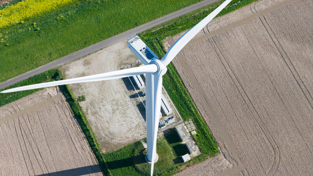 Aerial view of a large white wind turbine with its blades and nacelle above an electrical station and agricultural fields in Ooltgensplaat Zuid Holland Netherlands. Aerial view of a large white wind turbine with its blades and nacelle above an electrical station and agricultural fields in Ooltgensplaat Zuid Holland Netherlands.