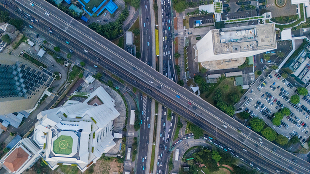 Aerial view of a highway overpass crossing through the urban landscape with skyscrapers parking lots and traffic in Jakarta Indonesia.