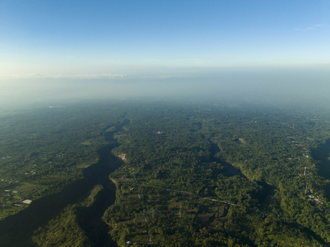 Aerial view of Kali Gendol river valley surrounded by dense tropical forests and rural settlements under a clear blue sky Cangkringan Special Region of Yogyakarta Indonesia.