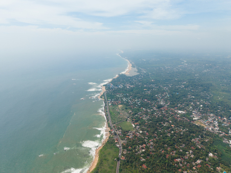 Aerial view of the scenic coastline featuring a sandy beach turquoise ocean waves and lush tropical vegetation along the coastal road in Galle Southern Province Sri Lanka. Aerial view of the scenic coastline featuring a sandy beach turquoise ocean waves and lush tropical vegetation along the coastal road in Galle Southern Province Sri Lanka.