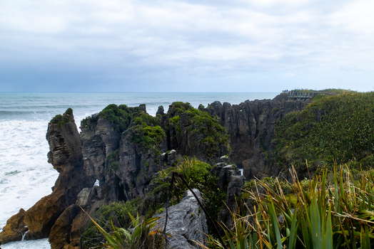 View of jagged rock formations meet the turbulent sea under a cloudy sky Pancake Rocks and Blowholes Walk West Coast Region New Zealand. View of jagged rock formations meet the turbulent sea under a cloudy sky Pancake Rocks and Blowholes Walk West Coast Region New Zealand.
