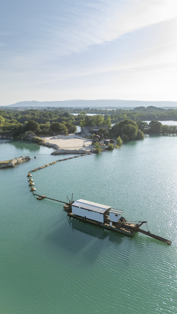 Aerial view of the Extraccion de aridos Lima SL dredging operation on a turquoise lake surrounded by lush green vegetation and rolling hills in Vilarino das Poldras Ourense Spain. Aerial view of the Extraccion de aridos Lima SL dredging operation on a turquoise lake surrounded by lush green vegetation and rolling hills in Vilarino das Poldras Ourense Spain.