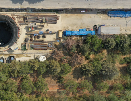 Aerial view of a construction site featuring a large circular excavation shaft and building materials next to a lush green forest in Avcilar Istanbul Turkiye. Aerial view of a construction site featuring a large circular excavation shaft and building materials next to a lush green forest in Avcilar Istanbul Turkiye.