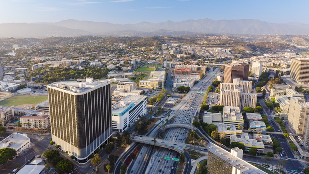 Aerial view of the busy 101 freeway winding through the urban landscape with high rise buildings and distant mountains under a clear sky in Los Angeles California United States.