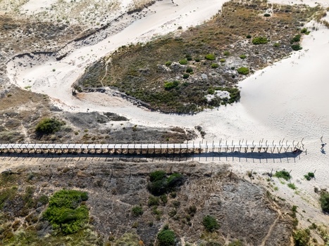 Aerial view of the wooden boardwalk stretching across the sand dunes and coastal vegetation at Praia do Guincho in Cascais Lisbon Portugal. Aerial view of the wooden boardwalk stretching across the sand dunes and coastal vegetation at Praia do Guincho in Cascais Lisbon Portugal.