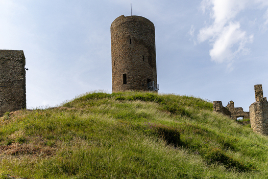 View of Monreal Castle ruins featuring a tall stone tower on a grassy hill under a bright sky Monreal Rheinland Pfalz Germany. View of Monreal Castle ruins featuring a tall stone tower on a grassy hill under a bright sky Monreal Rheinland Pfalz Germany.
