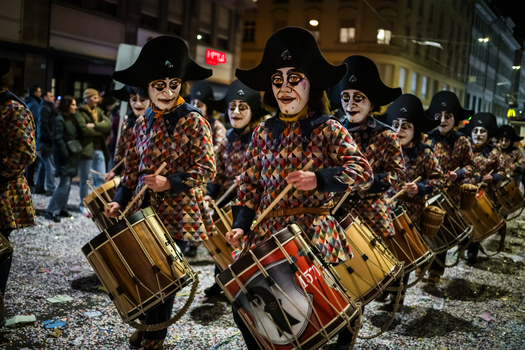 Basel Switzerland 10 March 2025 View of drummers marching with harlequin costumes black hats and painted faces their drums reflecting the city s lights and the festive spirit of Fasnacht. Basel Switzerland 10 March 2025 View of drummers marching with harlequin costumes black hats and painted faces their drums reflecting the city s lights and the festive spirit of Fasnacht.