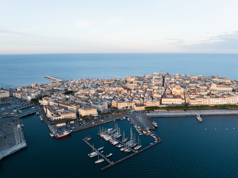 Aerial view of the Island of Ortigia with its historic architecture harbor filled with sailboats and the deep blue Mediterranean Sea Syracuse Sicily Italy. Aerial view of the Island of Ortigia with its historic architecture harbor filled with sailboats and the deep blue Mediterranean Sea Syracuse Sicily Italy.