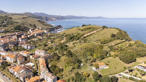 Aerial view of the coastal town of Zumaia featuring residential buildings nestled among green hills and rugged cliffs overlooking the Atlantic Ocean in Zumaia Basque Country Spain.