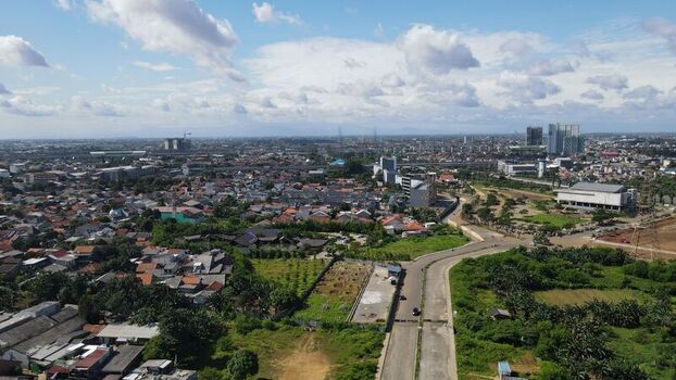 Aerial view of Jakasampurna featuring dense residential rooftops green vegetation and urban infrastructure under a cloudy sky in Bekasi Barat West Java Indonesia. Aerial view of Jakasampurna featuring dense residential rooftops green vegetation and urban infrastructure under a cloudy sky in Bekasi Barat West Java Indonesia.