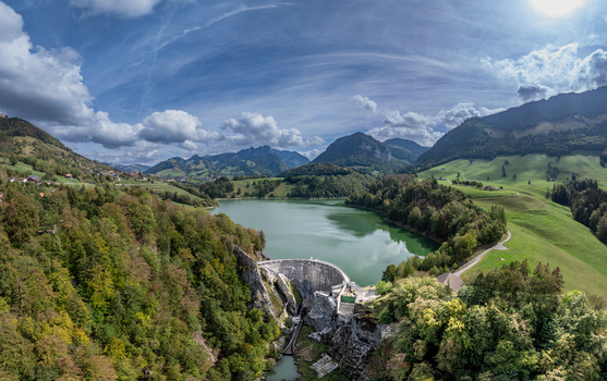 Aerial view of Barrage de Montsalvens dam and the surrounding reservoir nestled among lush green hills and forests in Chatel sur Montsalvens Fribourg Switzerland. Aerial view of Barrage de Montsalvens dam and the surrounding reservoir nestled among lush green hills and forests in Chatel sur Montsalvens Fribourg Switzerland.