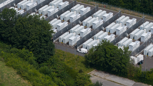 Aerial view of the RWE Power AG battery storage facility at Kraftwerk Neurath featuring rows of white energy storage containers and a van in Grevenbroich Nordrhein Westfalen Germany.