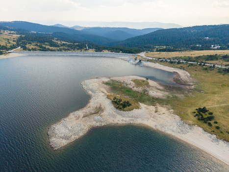 Aerial view of Belmeken Reservoir with its expansive water surface rocky shoreline and surrounding forested mountains in Pazardzhik Bulgaria. Aerial view of Belmeken Reservoir with its expansive water surface rocky shoreline and surrounding forested mountains in Pazardzhik Bulgaria.