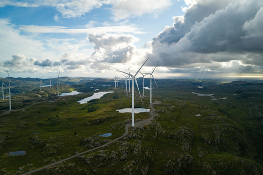 Aerial view of Makaknuten Wind Farm with wind turbines standing on a rocky green landscape with small ponds under a dramatic cloudy sky in Bjerkreim Municipality Rogaland Norway. Aerial view of Makaknuten Wind Farm with wind turbines standing on a rocky green landscape with small ponds under a dramatic cloudy sky in Bjerkreim Municipality Rogaland Norway.