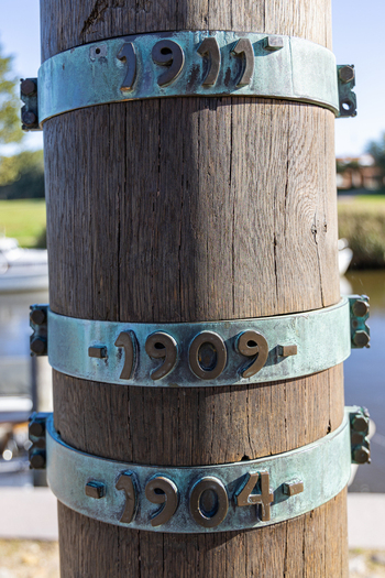 View of the Stormflodssojlen flood column showing historical water levels on weathered metal rings attached to a textured wooden pole Ribe Denmark. View of the Stormflodssojlen flood column showing historical water levels on weathered metal rings attached to a textured wooden pole Ribe Denmark.