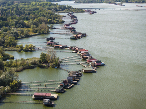 Aerial view of the colorful wooden houses on stilts at Bokodi Floating Village connected by wooden walkways over the lake in Oroszlany Hungary. Aerial view of the colorful wooden houses on stilts at Bokodi Floating Village connected by wooden walkways over the lake in Oroszlany Hungary.