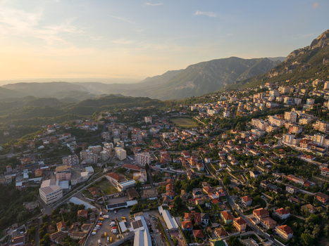 Aerial view of the historic town of Kruje nestled on a mountain slope with red tiled rooftops and lush greenery under a warm sunset light Kruje Durres County Albania.