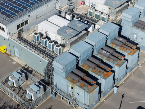 Aerial view of a data center facility with industrial cooling units HVAC systems and solar panels on the roof plus electrical transformers in a fenced enclosure in the United Kingdom.