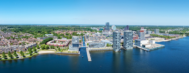 Aerial view of the modern skyline of Almere featuring contemporary high rise buildings along the waterfront urban residential areas and green spaces in Almere Flevoland Netherlands. Aerial view of the modern skyline of Almere featuring contemporary high rise buildings along the waterfront urban residential areas and green spaces in Almere Flevoland Netherlands.
