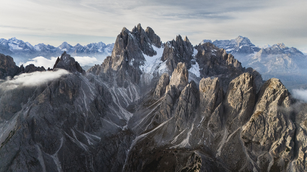 Aerial view of the jagged peaks of the Cadini group with rocky ridges and light snow under a cloudy sky in Auronzo di Cadore Veneto Italy. Aerial view of the jagged peaks of the Cadini group with rocky ridges and light snow under a cloudy sky in Auronzo di Cadore Veneto Italy.