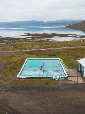 Aerial view of a geothermal pool reflecting the sky nestled amidst Iceland s rugged landscape with distant mountains Westfjords Iceland. Aerial view of a geothermal pool reflecting the sky nestled amidst Iceland s rugged landscape with distant mountains Westfjords Iceland.