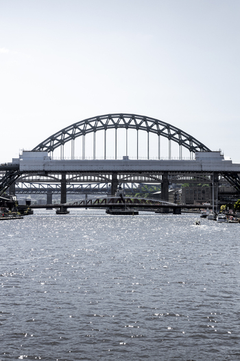 View of the iconic Tyne Bridge spanning the river Tyne with shimmering water and a clear sky in Newcastle upon Tyne England United Kingdom. View of the iconic Tyne Bridge spanning the river Tyne with shimmering water and a clear sky in Newcastle upon Tyne England United Kingdom.