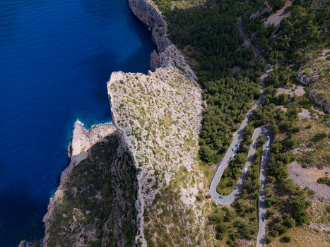 Aerial view of the winding road at Cap de Formentor with hairpin turns along steep rocky cliffs overlooking the deep blue sea in Balearic Islands Spain.