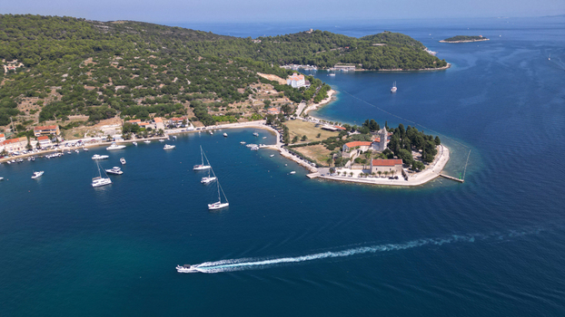 Aerial view of the Prirovo Franciscan Monastery on a peninsula with sailing boats in the bay and lush green hills Vis Split Dalmatia County Croatia. Aerial view of the Prirovo Franciscan Monastery on a peninsula with sailing boats in the bay and lush green hills Vis Split Dalmatia County Croatia.