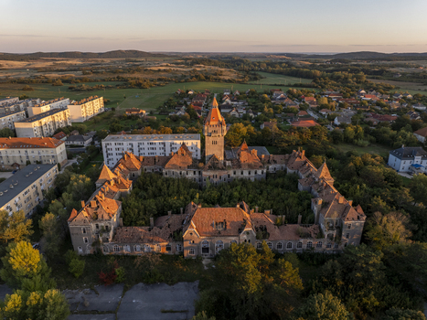 Aerial view of the abandoned Hajmasker Barracks with a central tower red roofs and an overgrown courtyard surrounded by historic military architecture in Hajmasker Hungary. Aerial view of the abandoned Hajmasker Barracks with a central tower red roofs and an overgrown courtyard surrounded by historic military architecture in Hajmasker Hungary.