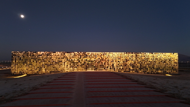 Aerial view of the Karapinar Solar Power Plant illuminated at night with golden lights featuring a modern reflective facade under a dark sky in Karapinar Konya Turkiye.