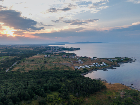 Aerial view of the coastal landscape at Arapya featuring small buildings lush green forests and rocky shorelines along the Black Sea during a soft sunset in Burgas Bulgaria. Aerial view of the coastal landscape at Arapya featuring small buildings lush green forests and rocky shorelines along the Black Sea during a soft sunset in Burgas Bulgaria.