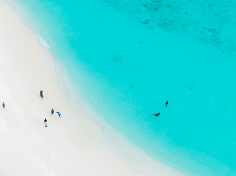 Aerial view of turquoise waters gently kiss the pristine white sands where tiny figures stroll Hoarafushi Thiladhunmathee Uthuruburi Maldives. Aerial view of turquoise waters gently kiss the pristine white sands where tiny figures stroll Hoarafushi Thiladhunmathee Uthuruburi Maldives.